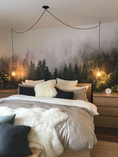 a bed with pillows and blankets in front of a forest mural on the wall behind it