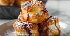 a pile of doughnuts sitting on top of a plate covered in powdered sugar