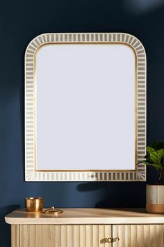 a mirror sitting on top of a wooden cabinet next to a potted green plant