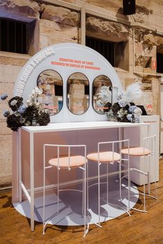 a counter with three stools in front of it and some flowers on the table