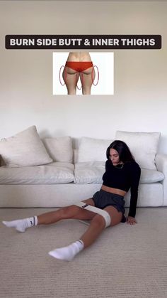 a woman sitting on the floor in front of a couch with her legs spread out