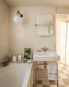 a white sink sitting under a bathroom mirror next to a bath tub