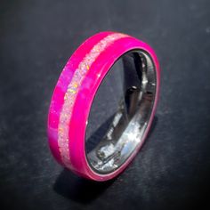 a pink ring with gold flecks on it sitting on a black table top