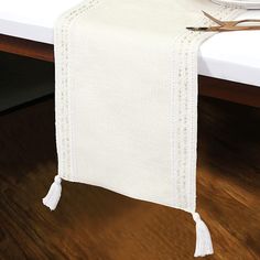 a white table runner with tassels on the edge and an empty plate next to it