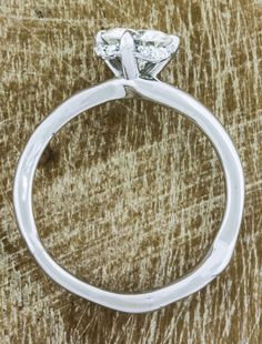 a close up of a diamond ring on a table with wood grained surface in the background