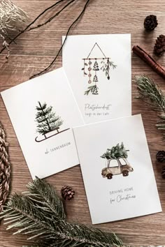 three cards with christmas trees on them sitting next to pine cones and twinklings