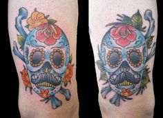 two tattoos on the legs of people with skulls and flowers in their hair, one is blue