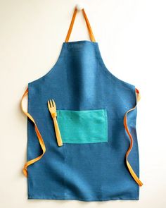 a blue apron with orange straps and a fork in the pocket, on a white background