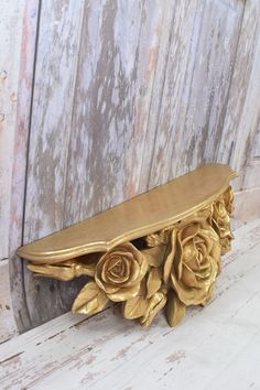 a wooden bench with flowers on it sitting against a door frame in front of a weathered wall