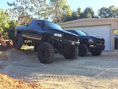 two black trucks parked in front of a garage