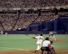 a baseball player swinging a bat on top of a field in front of a crowd