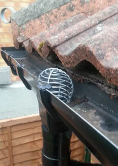 a grill sitting on top of a roof next to a gutter hose and pipe