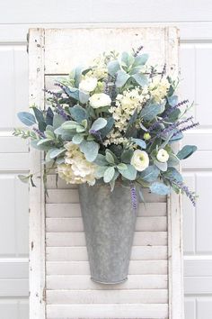 a vase filled with white flowers sitting on top of a wooden chair in front of a garage door