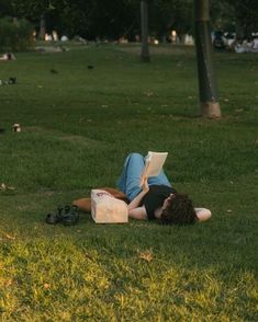 a person laying on the grass reading a book