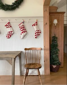 three stockings hung on the wall above a wooden table with a chair in front of it