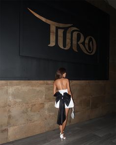 a woman in a black and white dress standing next to a sign that reads tro