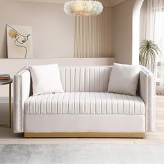 a white couch sitting next to a table with a lamp on it's side