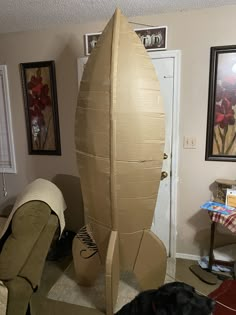 a cardboard rocket ship sitting on top of a living room floor next to a black dog