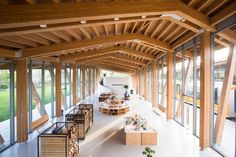 the inside of a building with lots of windows and wooden beams on the ceiling is filled with furniture