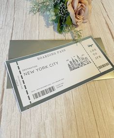 a ticket sitting on top of a wooden table next to a bouquet of flowers and a rose