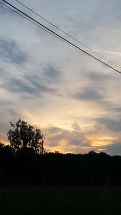 a person flying a kite in the air at sunset or dawn with power lines above