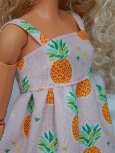 the doll is wearing a pink dress with pineapples on it's chest