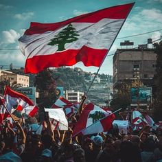 many people are holding flags and waving their hands in the air while one person holds up a flag