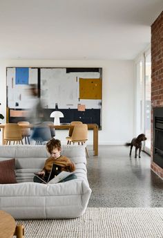 a young boy sitting on top of a couch in a living room next to a fire place