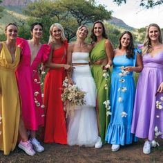 a group of women standing next to each other in long dresses and holding bouquets