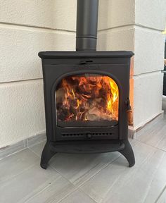 a wood burning stove in front of a white house with tile flooring and walls