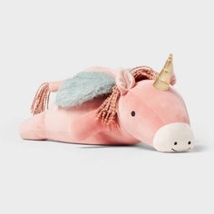 a pink stuffed unicorn laying down with a gold horn on its head and eyes closed