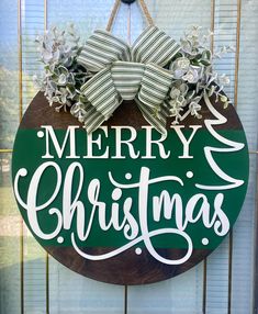 a merry christmas sign hanging on the side of a door with green and white ribbon