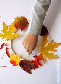 a child's hand on a wreath made out of leaves