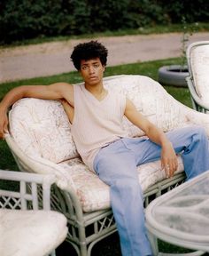 a young man sitting on top of a white chair next to other chairs and tables