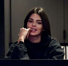 a woman sitting at a table with her hand on her chin and looking off to the side