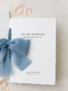 a wedding card with a blue ribbon tied to it and flowers around the front cover