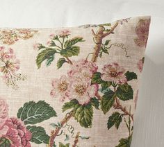 a pink flowered pillow sitting on top of a white couch