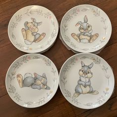 four plates with cartoon animals painted on them sitting on a wooden table next to each other