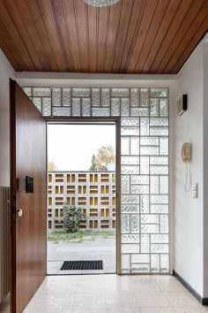 an open door leading into a room with white tile flooring and wood paneling