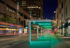 an empty sidewalk with chairs and tables lit up at night