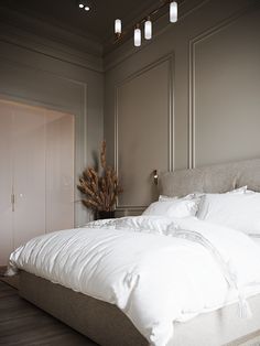 a bed with white linens and pillows in a large room next to a closet