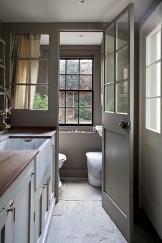 an open door leading to a bathroom with a sink and toilet next to a window