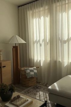 a living room filled with furniture and a window covered in sheer curtains next to a coffee table