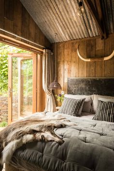 a large bed sitting next to a window in a wooden room with sliding glass doors