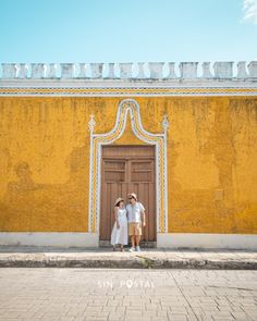 two people standing in front of a yellow building