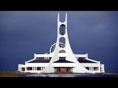 a large white building with a clock on it's side in front of a cloudy sky