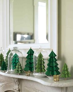 green paper christmas trees sitting on top of a table next to a mirror and fireplace