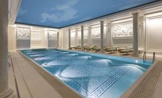 an indoor swimming pool with lounge chairs and blue sky in the backgrouds