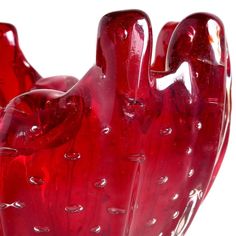 a red glass sculpture is shown against a white background with drops of water on it