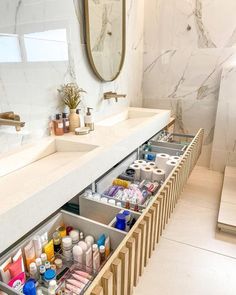 a bathroom with two sinks and drawers under the counter top is full of beauty products